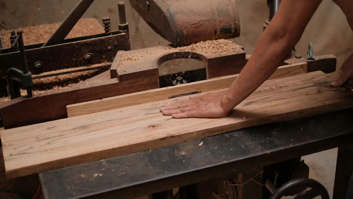 Holzbrett tritt mit glatter Oberfläche aus dem Auswurf eines Dickenhobels aus